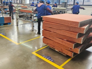 Workers handling stacked copper fin radiator cores in Sinrui factory